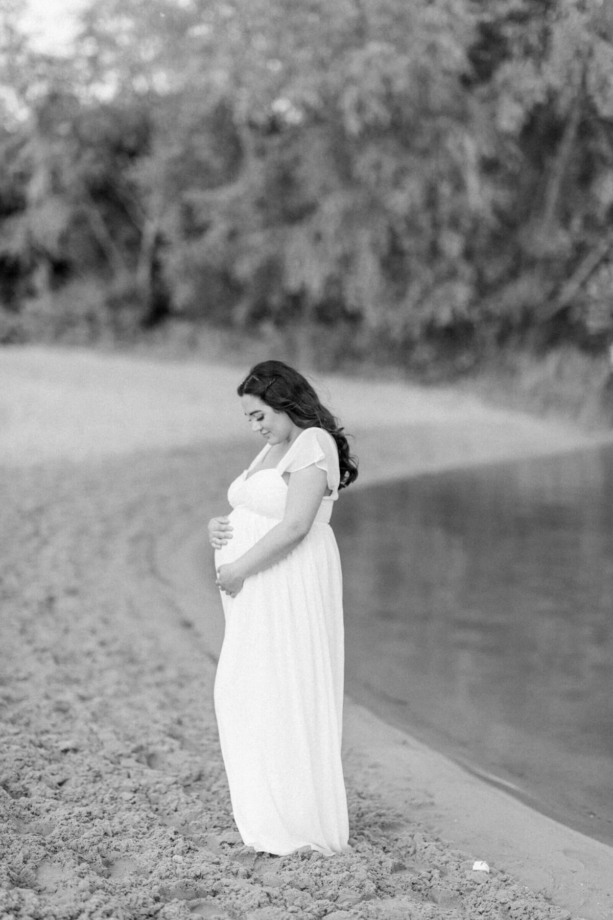 Zwangere vrouw in witte jurk op natuurlijke locatie