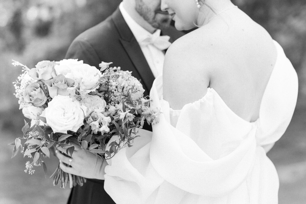 couple romantically embracing showing off bridal gown and bouquet