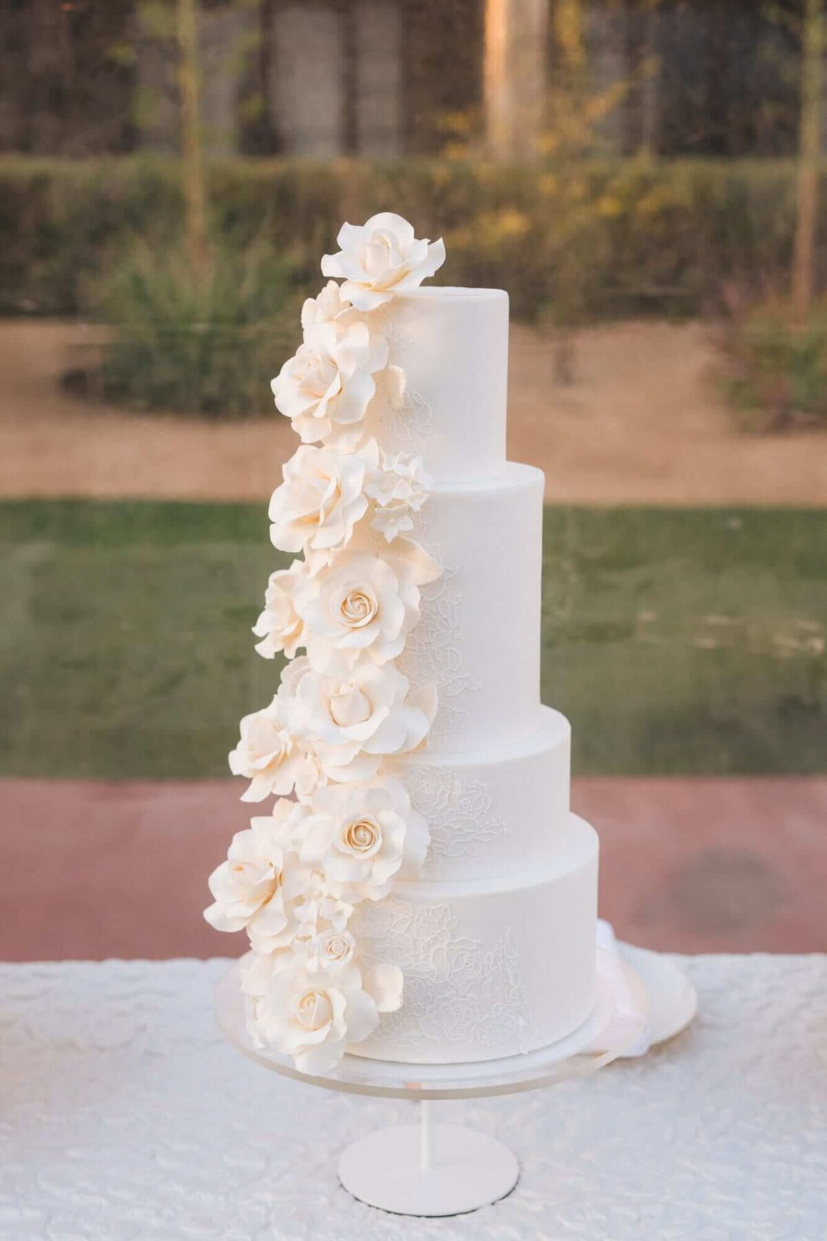 A four-tier Arizona Biltmore wedding cake decorated with cascading white sugar flowers, styled to reflect the luxury and sophistication of Scottsdale weddings.