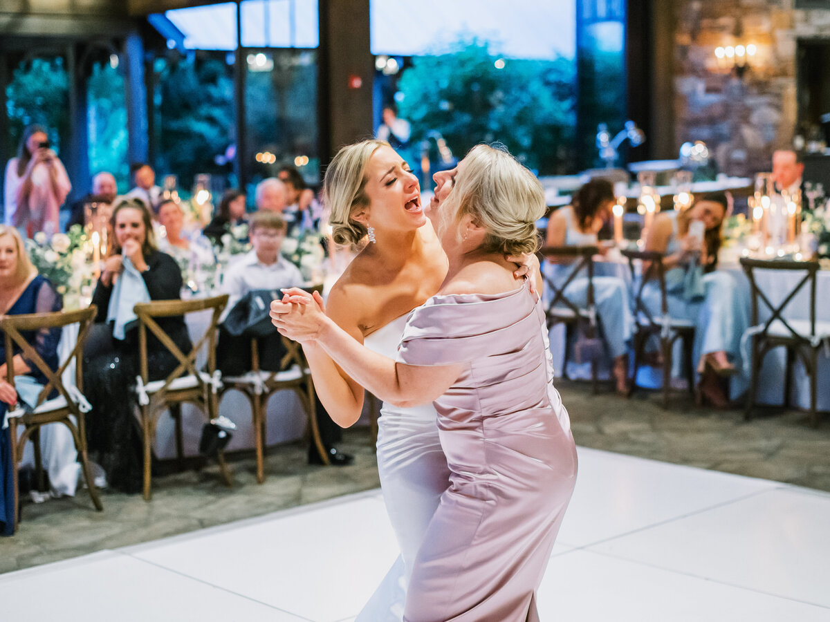Bride dances with her mother during the wedding reception at Old Edwards Inn in Highlands, North Carolina, surrounded by guests and candlelit tables.