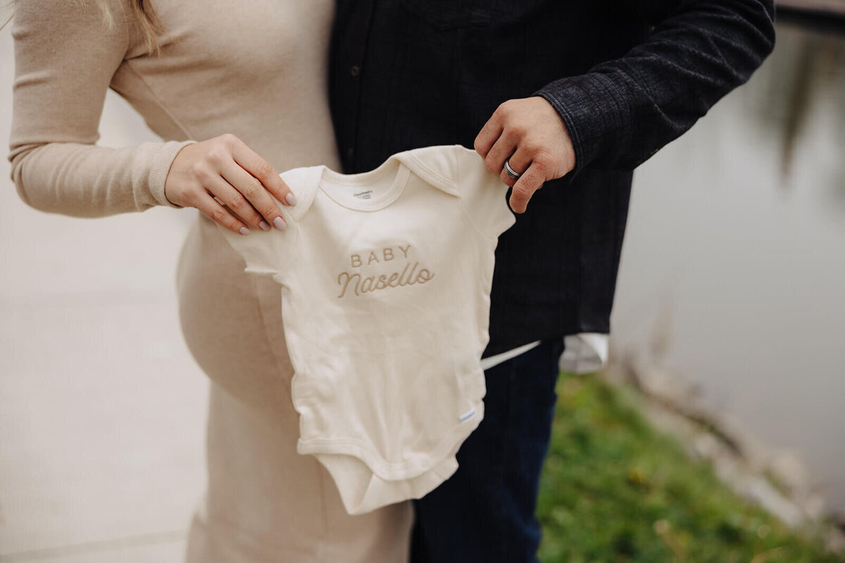 Couple holding baby onesie for pregnancy announcement