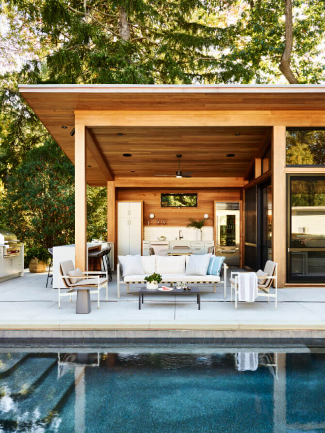 Modern pool house features outdoor furniture selected by interior design firms in Boston for a new construction home, blending style and comfort seamlessly.