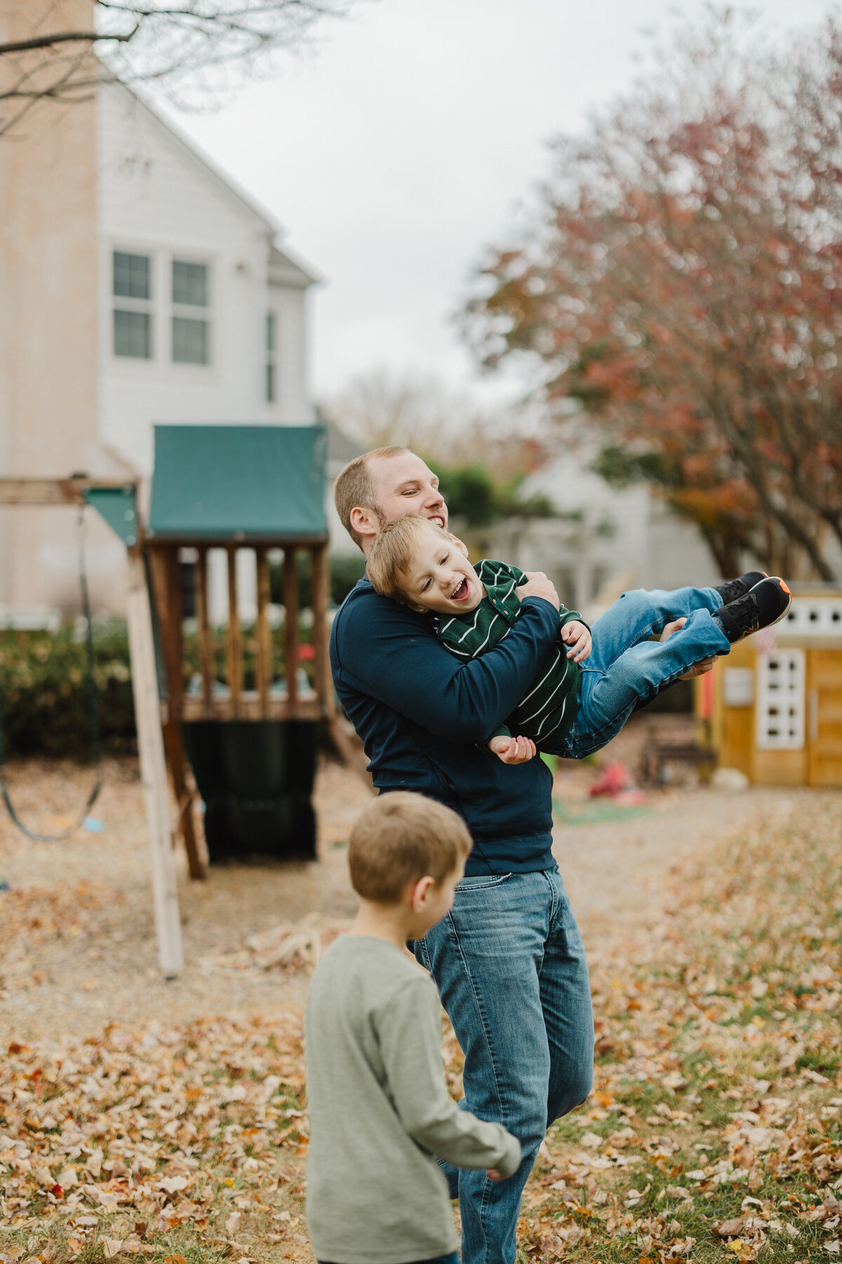 A parent has fun with their kids during fall.