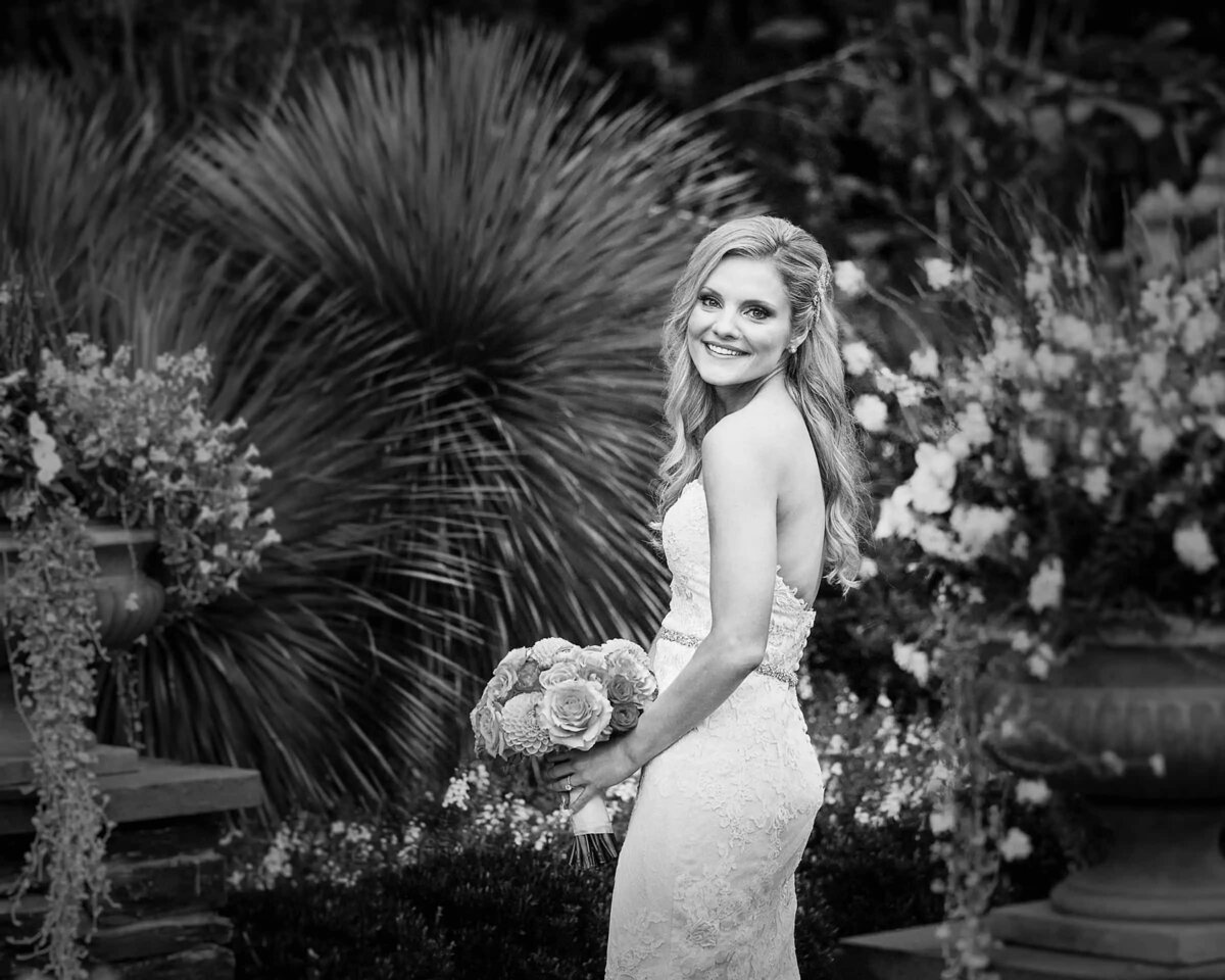 A bride smiling while holding a bouquet of flowers