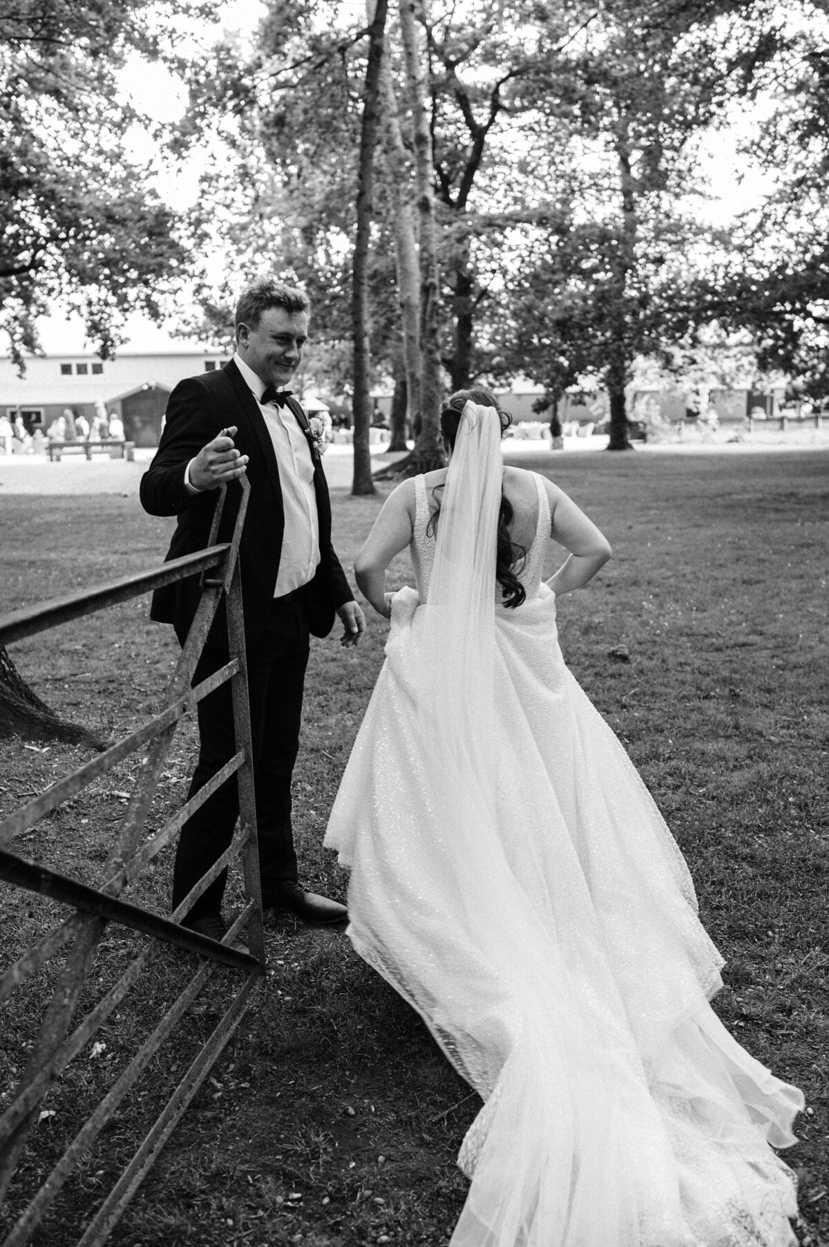 groom holds gate open for bride at bangor farm wedding venue near darfield