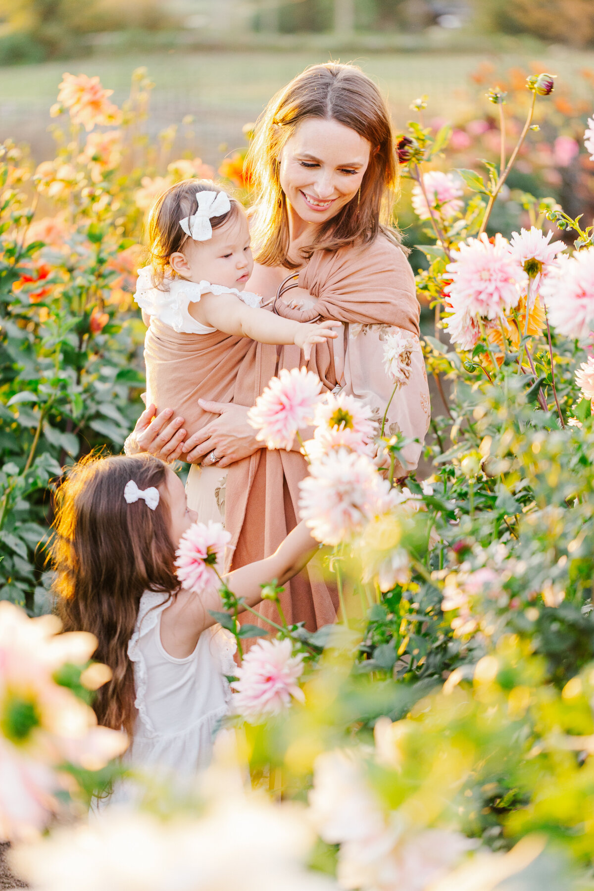 Mother with a baby on her hip and daughter standing next to her in a field of flowers