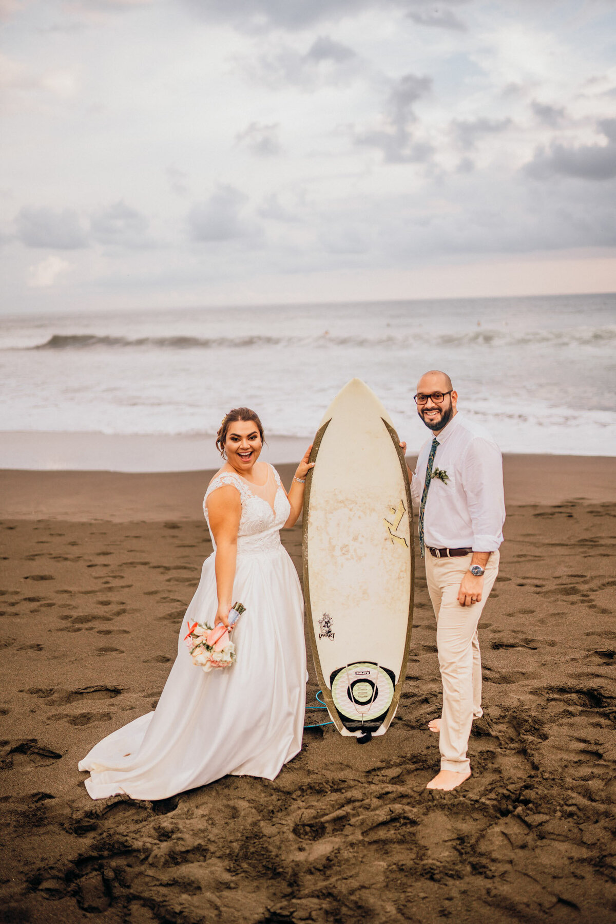 couple standing on beach with surf board