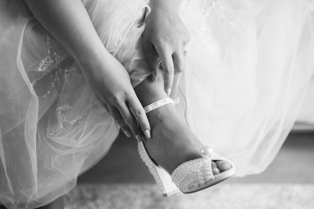 Bride putting on her wedding shoes covered in white pearls at the luxury destination wedding in Lake Como 