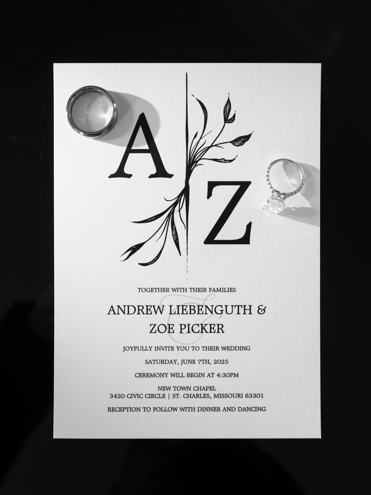 Modern black and white wedding invitation with rings placed on program