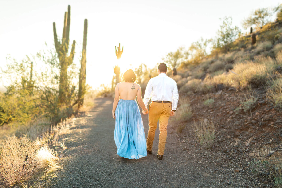 Photographer and owner of Cactus & Pine Photography with husband walking into desert sunset