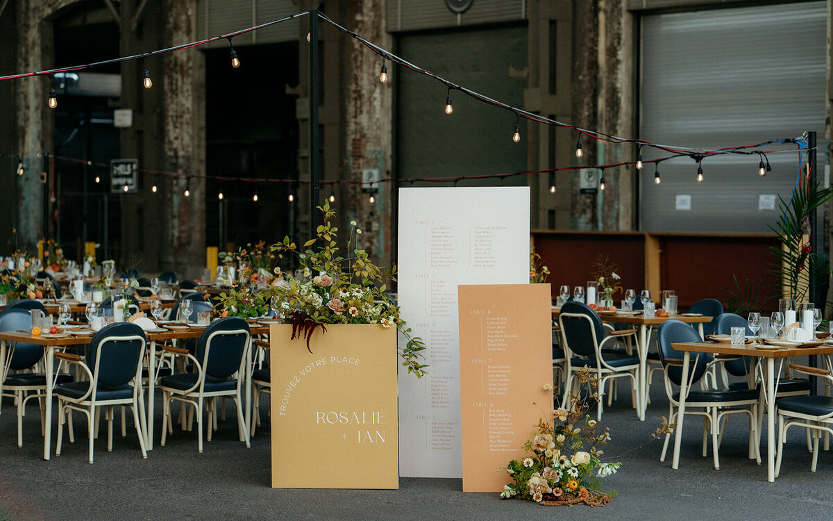 Bright place card signs are framed by colourful flowers at a Hoogan et Beaufort wedding reception.