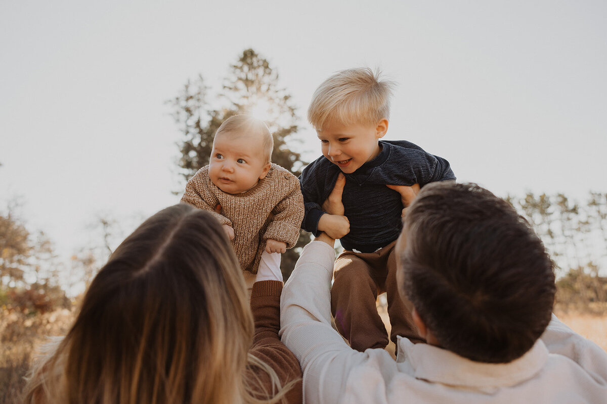 Mom and dad hold their kids up to the sunlight