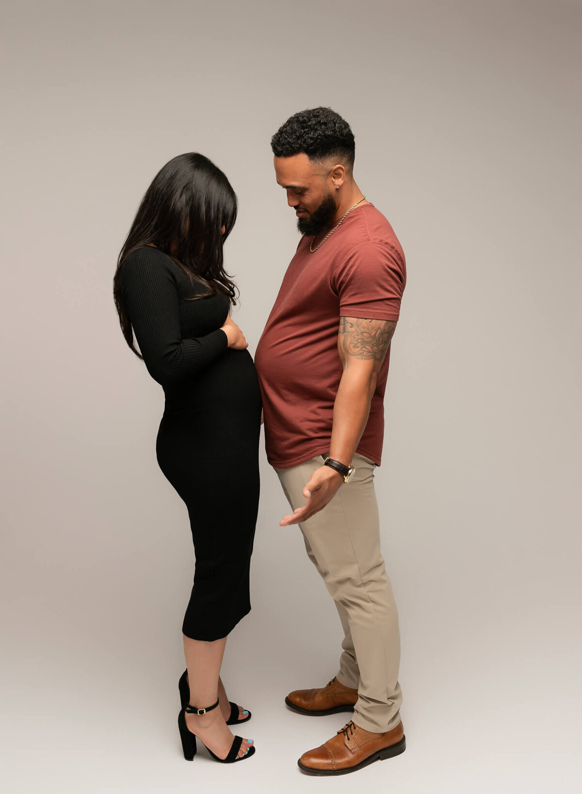 couple touching bellies together to announce their pregnancy during an austin photoshoot