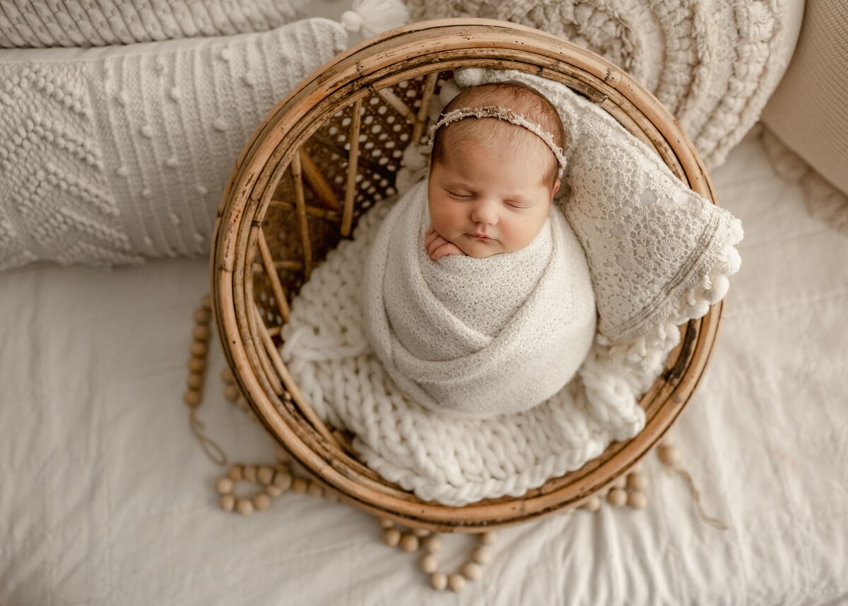 A newborn sleeps peacefully on a cozy neutral blanket during a minimalist studio newborn photoshoot in Denver.