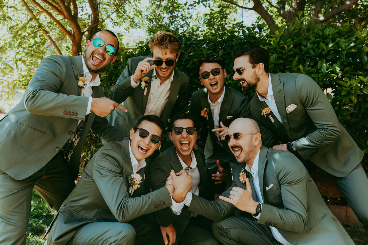 groomsmen smile and light with groom in green suits