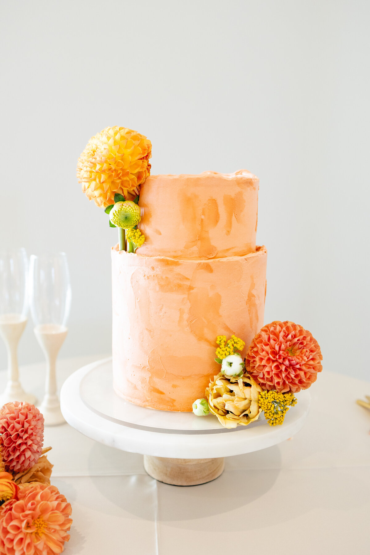 Bright and fun orange wedding cake with beautiful flower accents