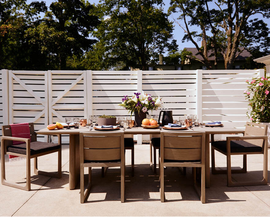 Enjoy the outdoor dining space at the pool area of a historic Hingham home, featuring weather-friendly wood furnishings with black cushions for a stylish and durable setup.