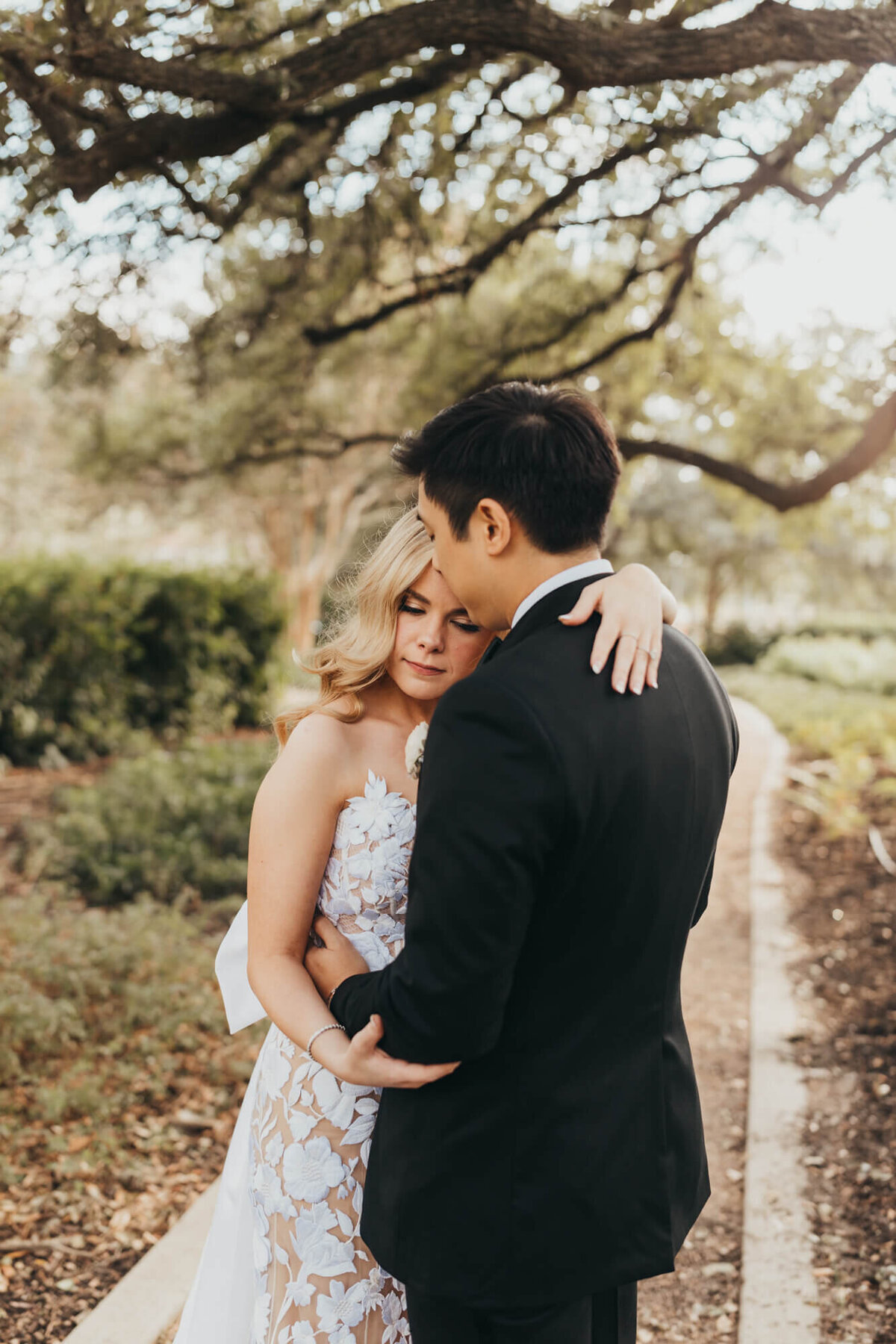 woman leans on her groom, wearing their wedding attire.