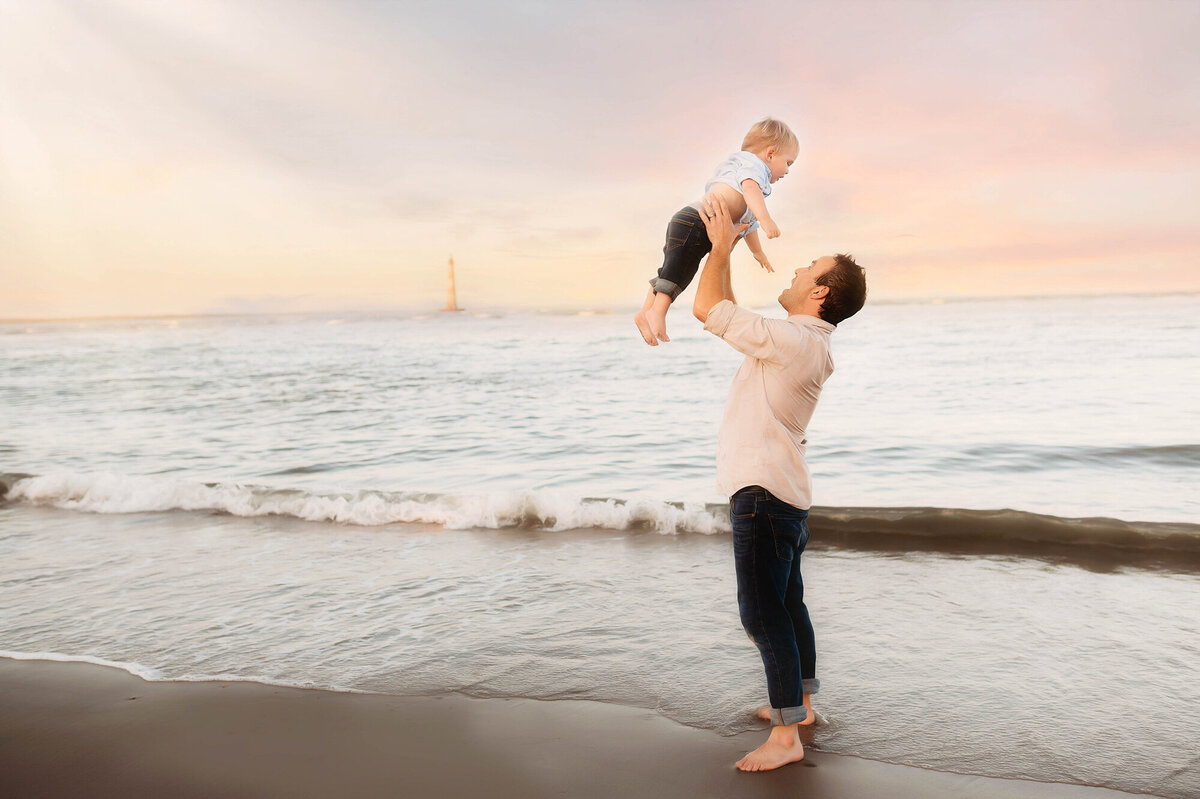 Father tosses his toddler in the air during Family Photoshoot on Folly Beach.