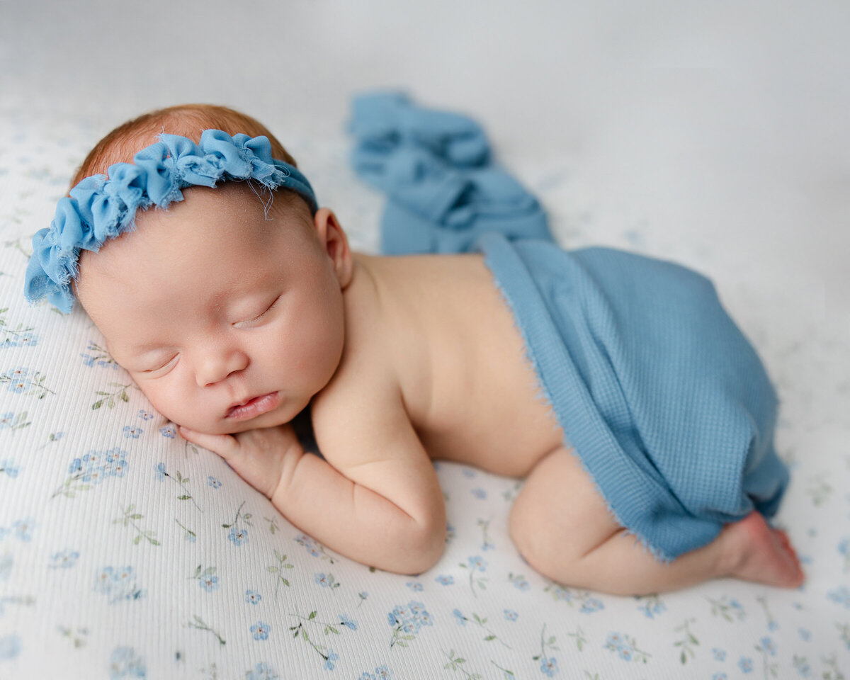 Sweet newborn girl lying on a soft blue blanket in a textured knit romper during his in-studio newborn session. Captured by Inland Empire baby photographer Kaitlyn Dawn Photography.