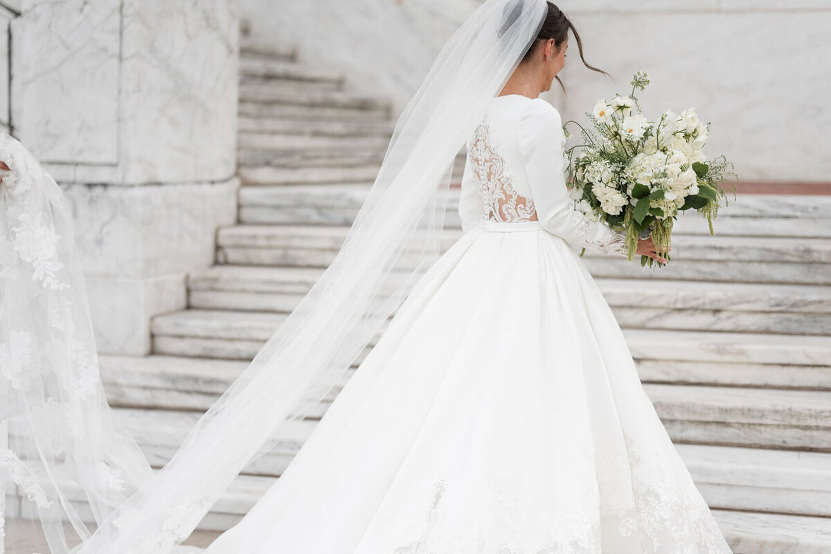 Wedding at Detroit Athletic Club, with bride walking up stairs holding a bouquet, taken by Detroit wedding photographer Courtney Rudicel
