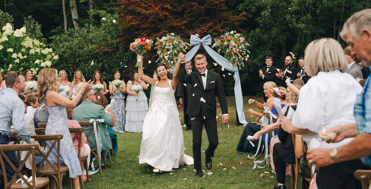 Wedding photography of a bride and groom celebrating as they are pronounced married heading down the aisle at Daras Garden Venue in Knoxville Tennessee.