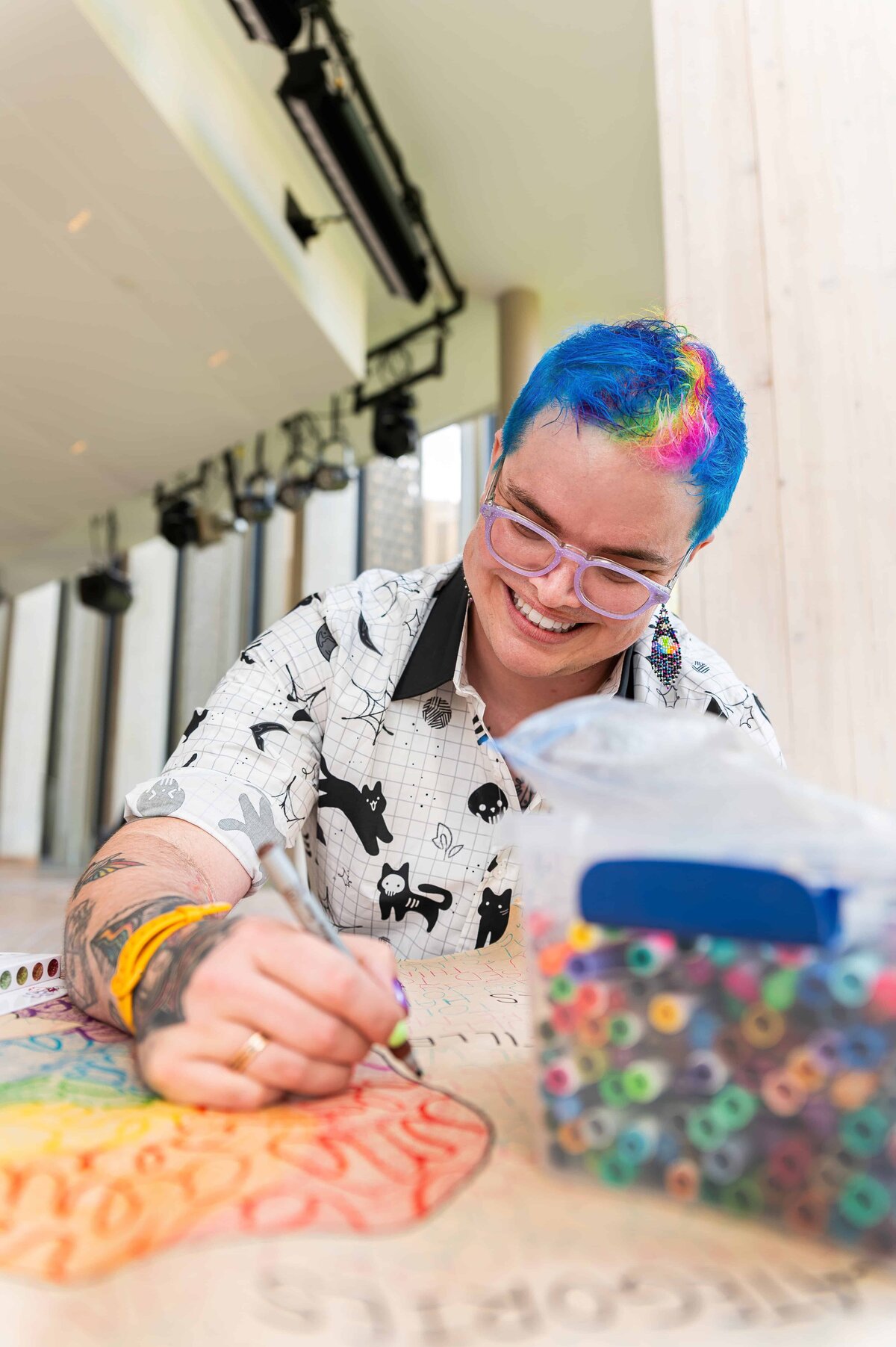 2SLGBTQIA+ artist and educator smiling and creating art at the National Arts Centre in Ottawa
