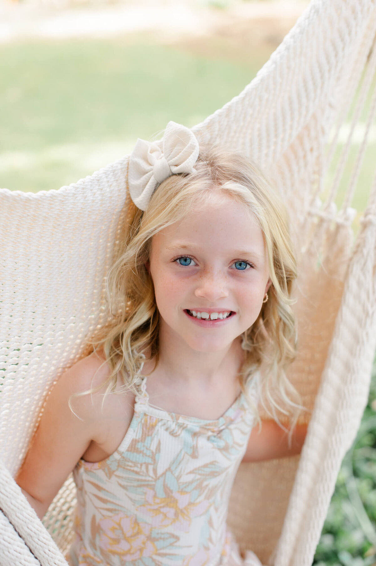 Young girl smiling at the camera while sitting in a hammock