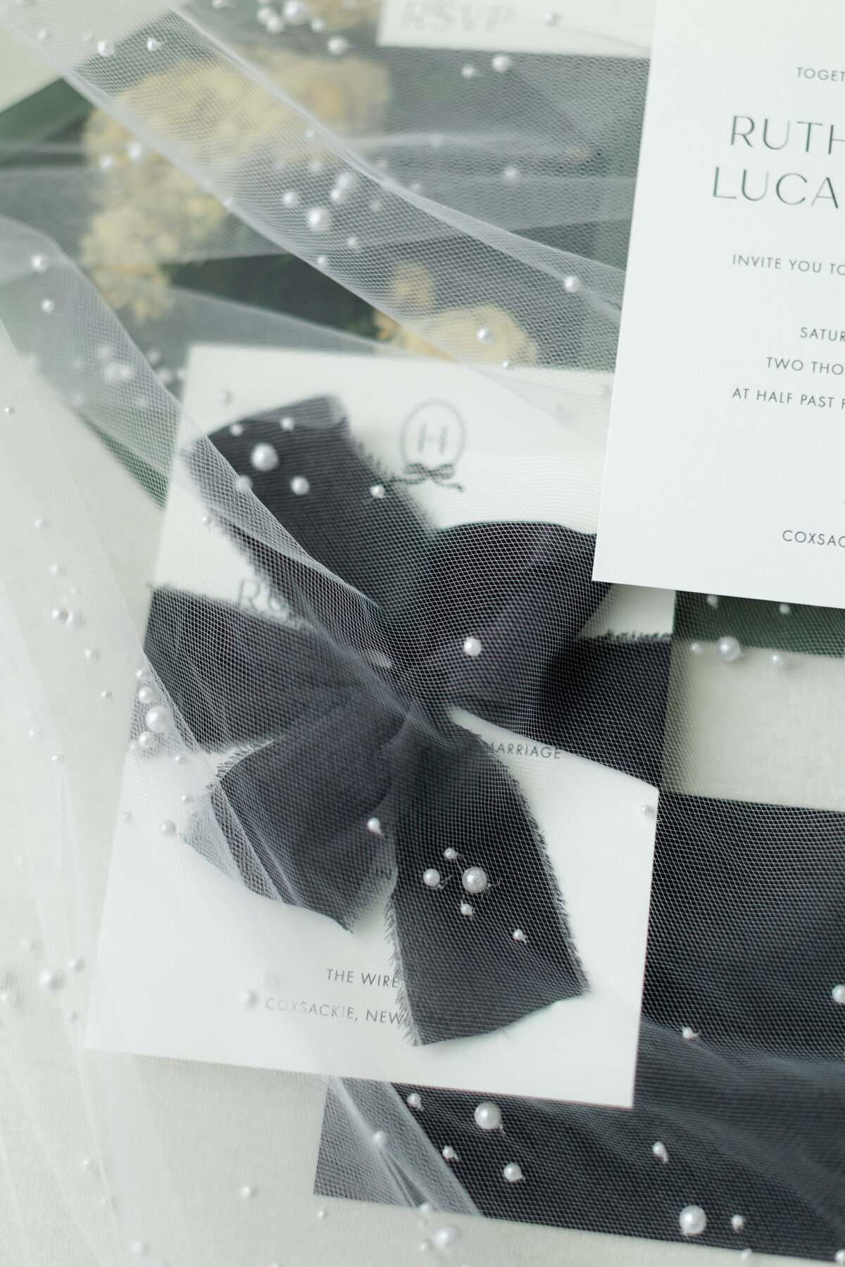 Detail shot of an invitation suit covered by a lace and pearl covered veil
