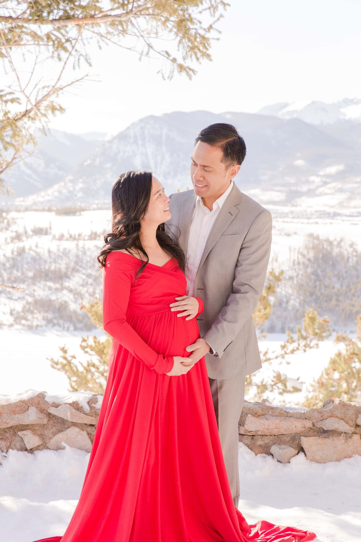 Husband touches belly bump with Rocky Mountains behind