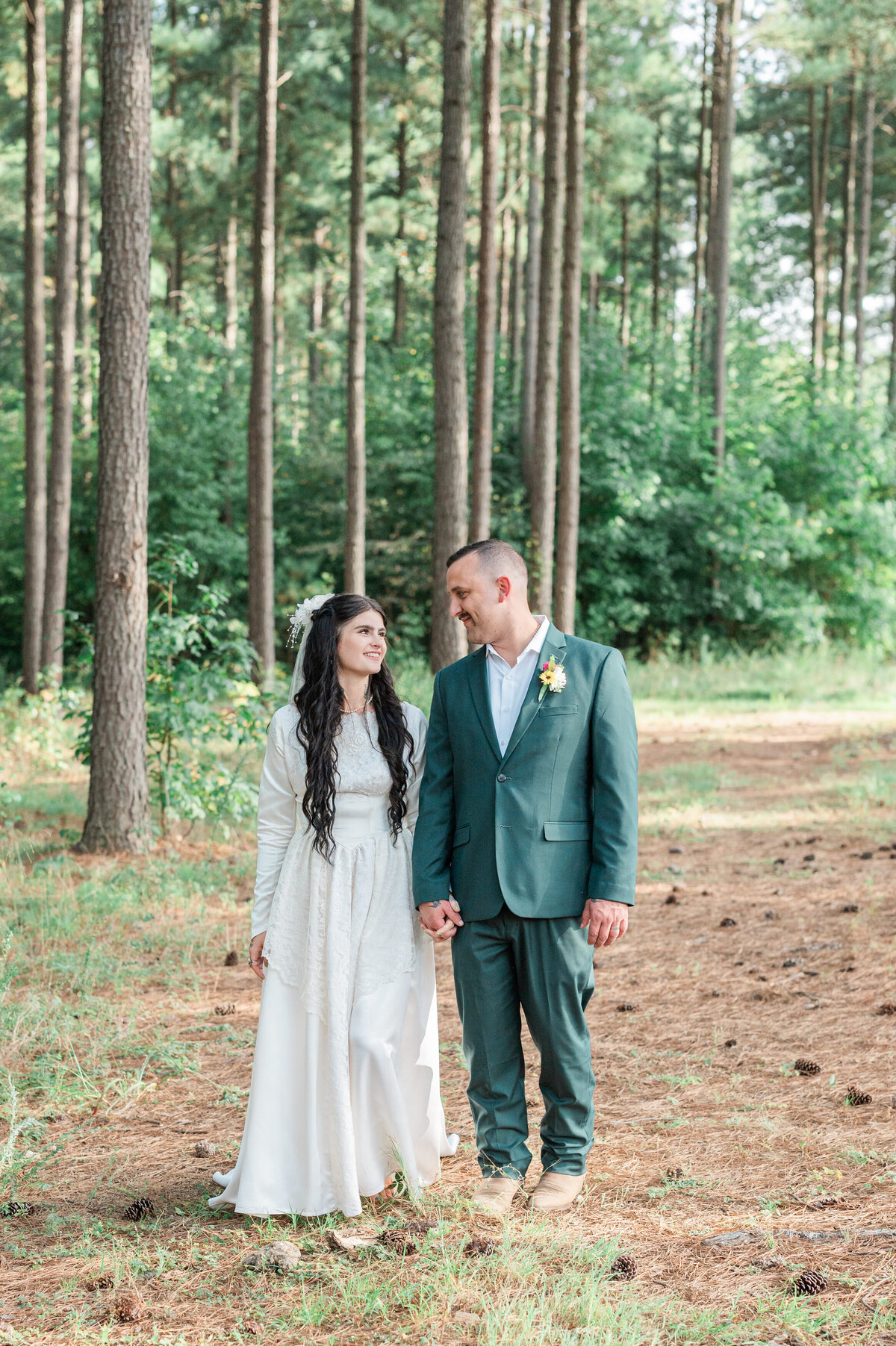 A couple holding hands and walking on a small path in between trees