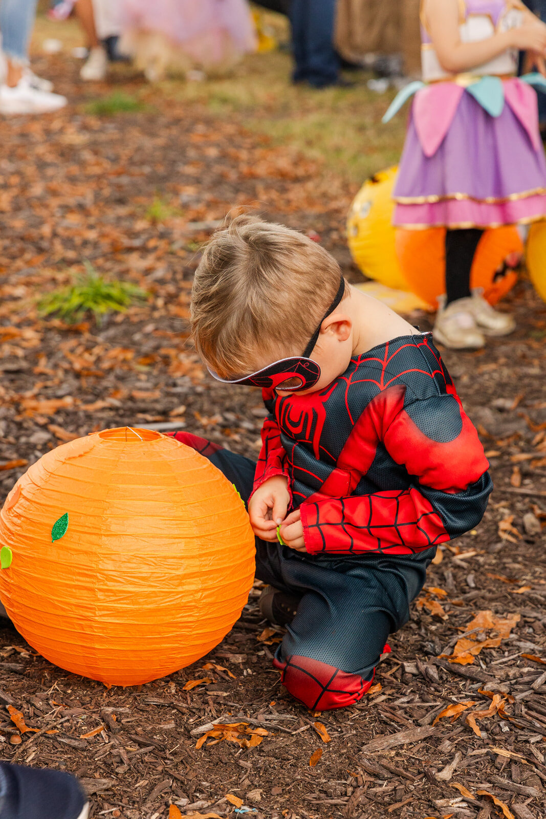 toddler boy dressed up and decorating his orange lantern during Fall Halloween festival in Brookhaven Atlanta GA