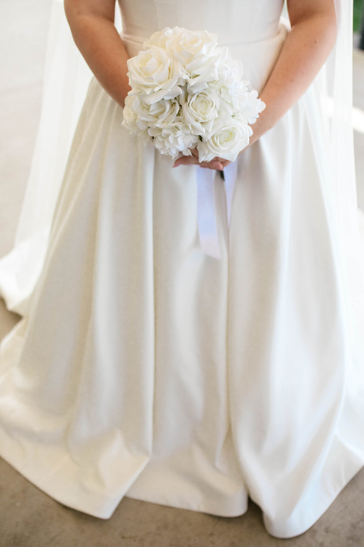 The bride holds onto her white bouquet. 