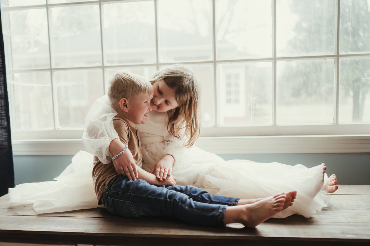 Bowling Green Kentucky family photographer. Smiths Grove Kentucky Photographer. Siblings snuggling in window.