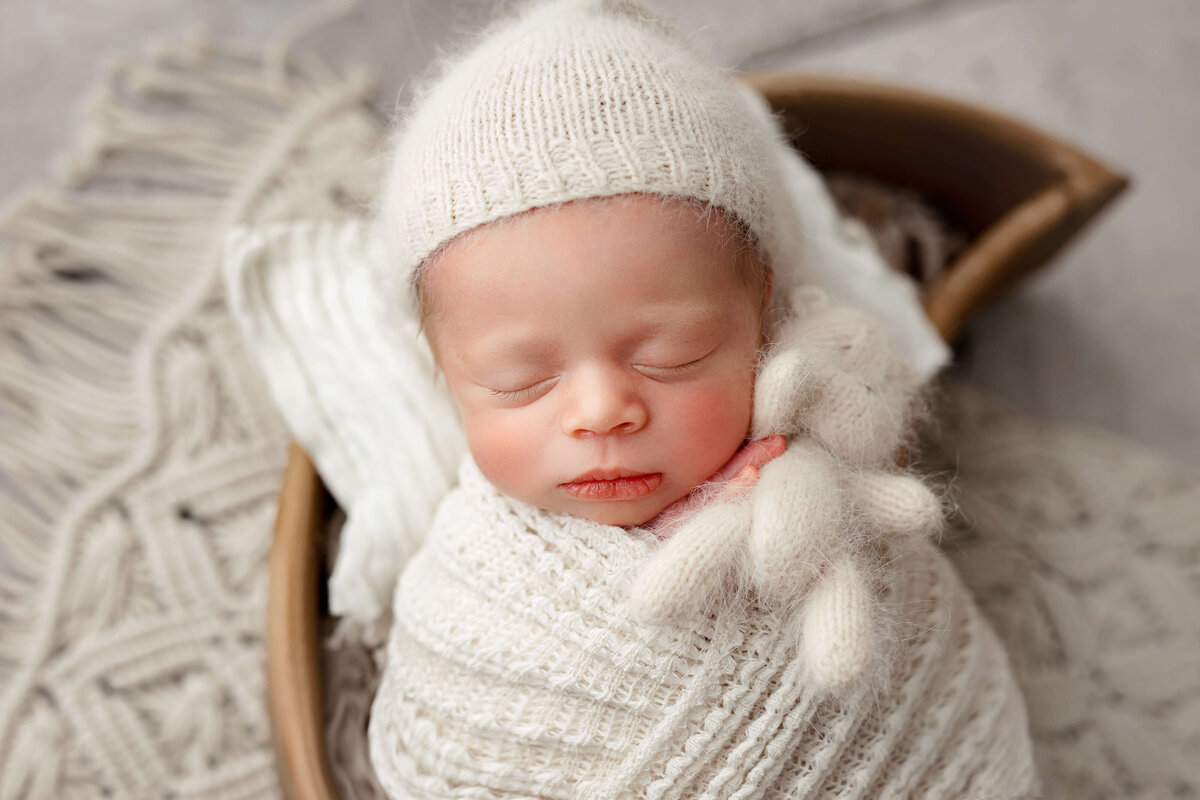 baby  in newborn photo session holding little white  bear