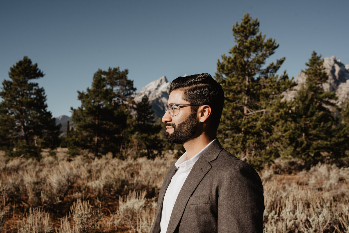 man in formal wear facing  the sun with the Grand Tetons in the background