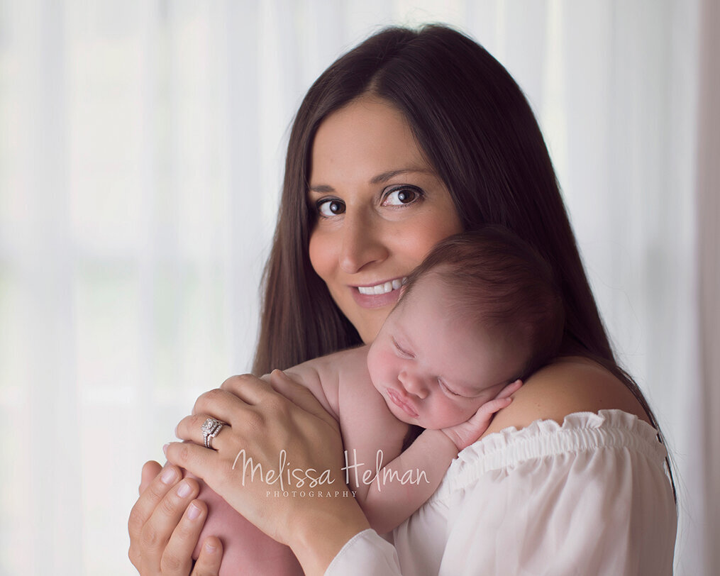 Mom holding daughter on shoulder in white shirt