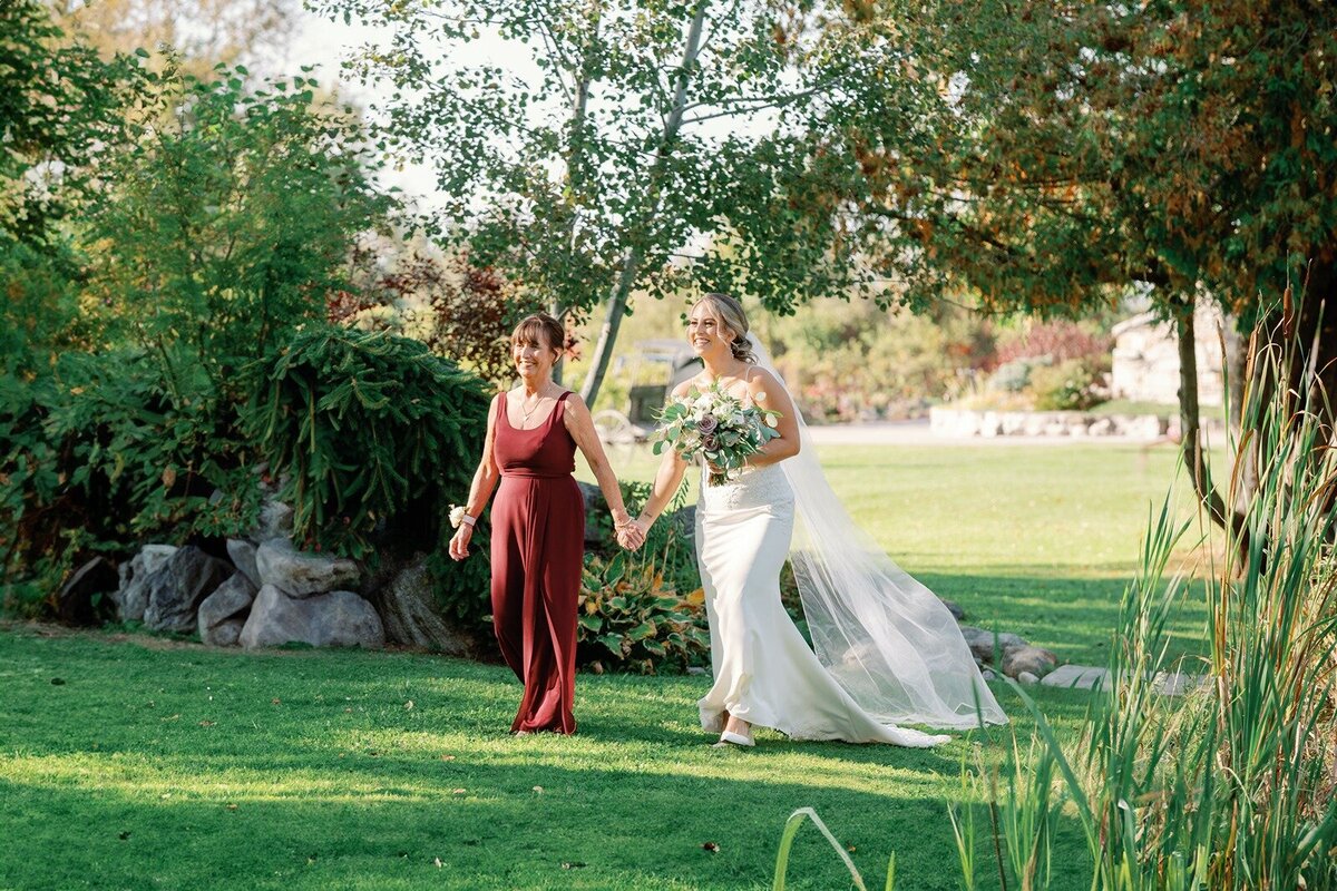 bride and bridesmaid walking through lush green scenery