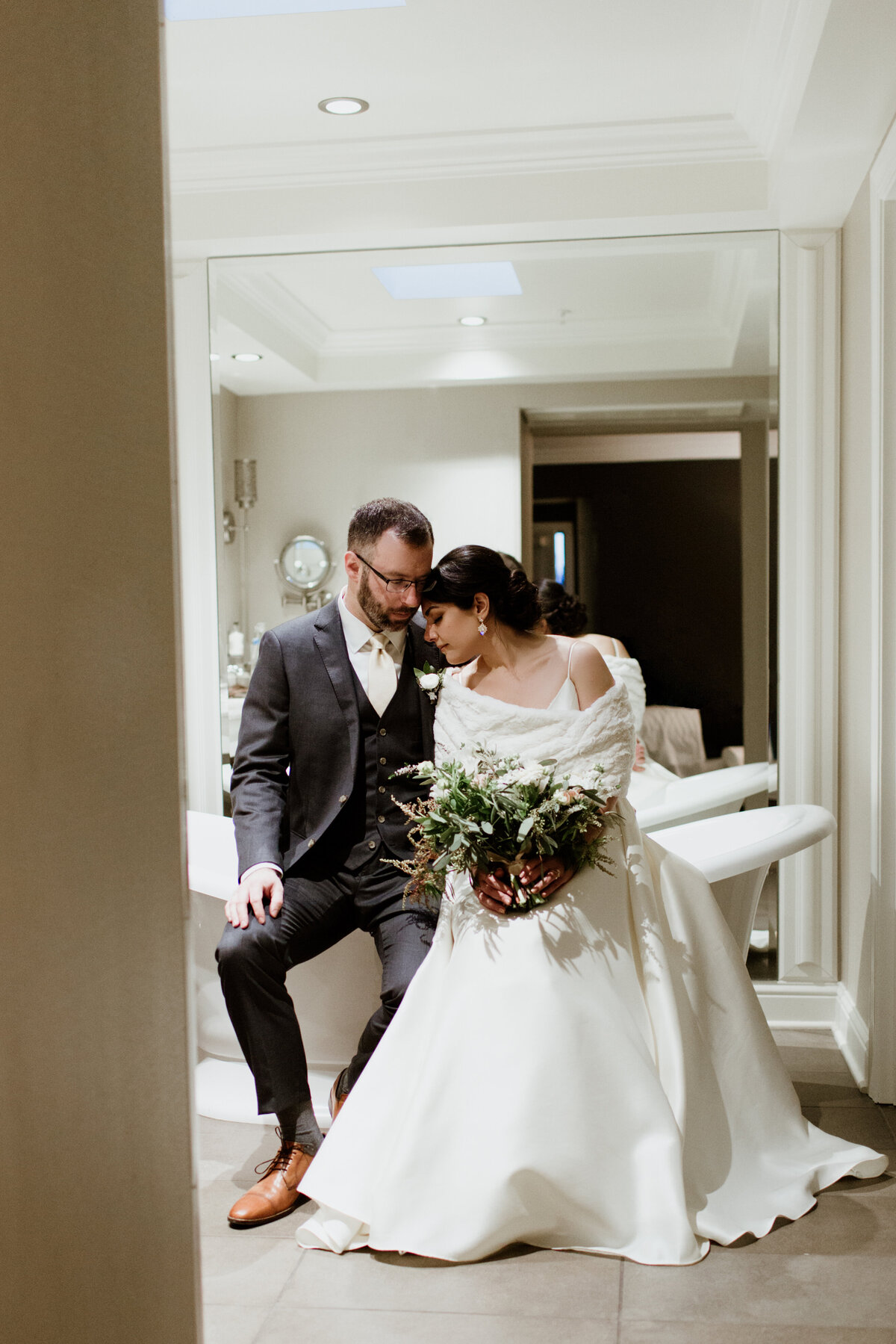 A quiet, romantic moment of a couple in wedding attire sitting in a hotel bathroom. Captured by Fort Worth wedding photographer, Megan Christine Studio