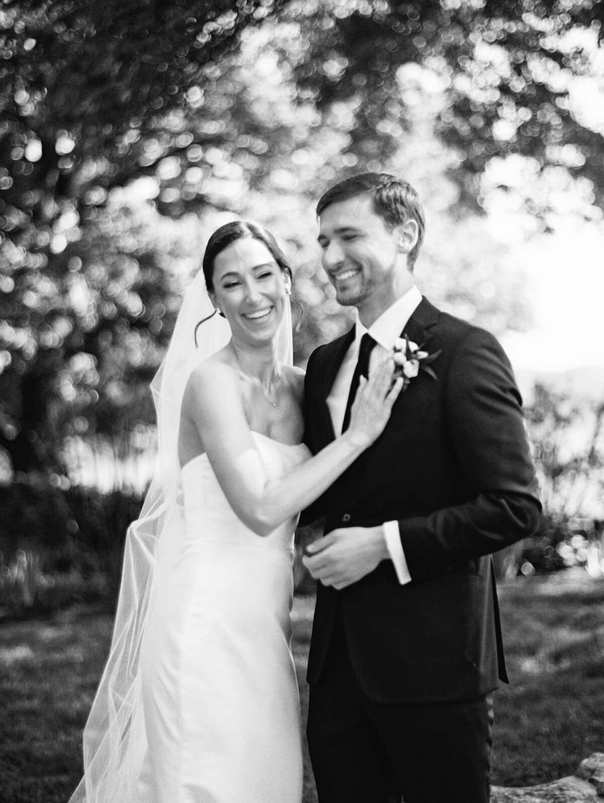 A black and white image of a bride and groom as they smile with joy
