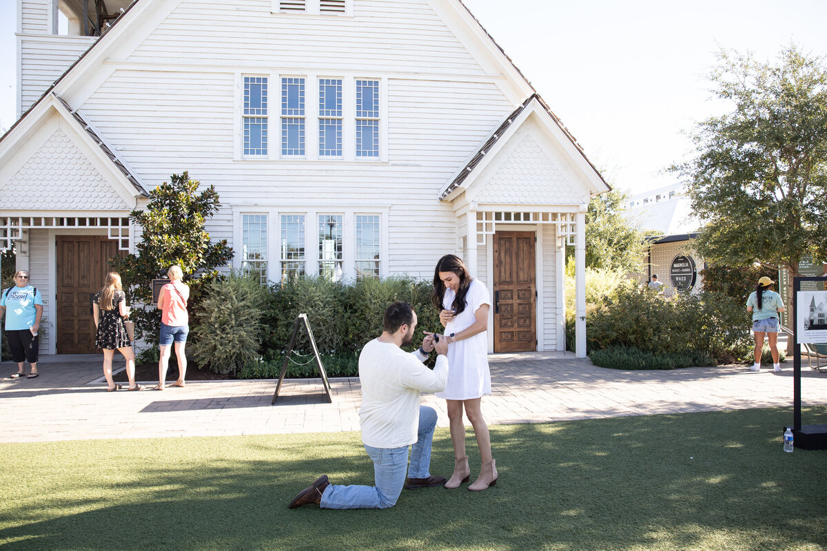 An Austin wedding photographer captures the moment a man proposes to a woman in front of a white house.