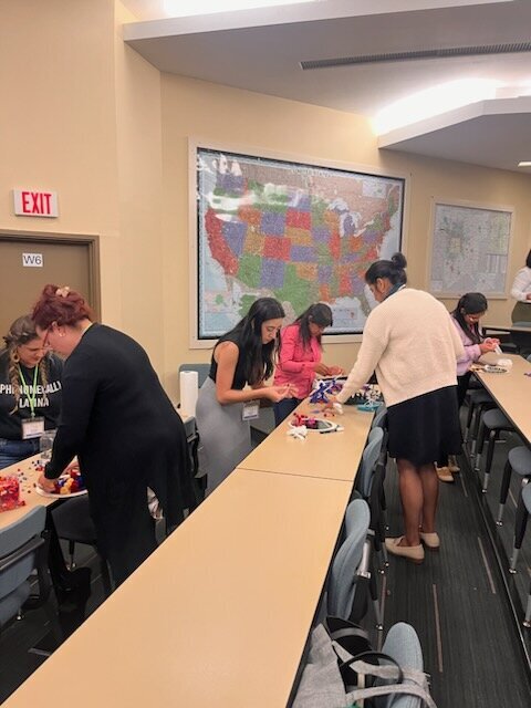 the magic as a group of women gathers around a rectangular wooden table, working collaboratively on crafting a radiant mirror masterpiece.