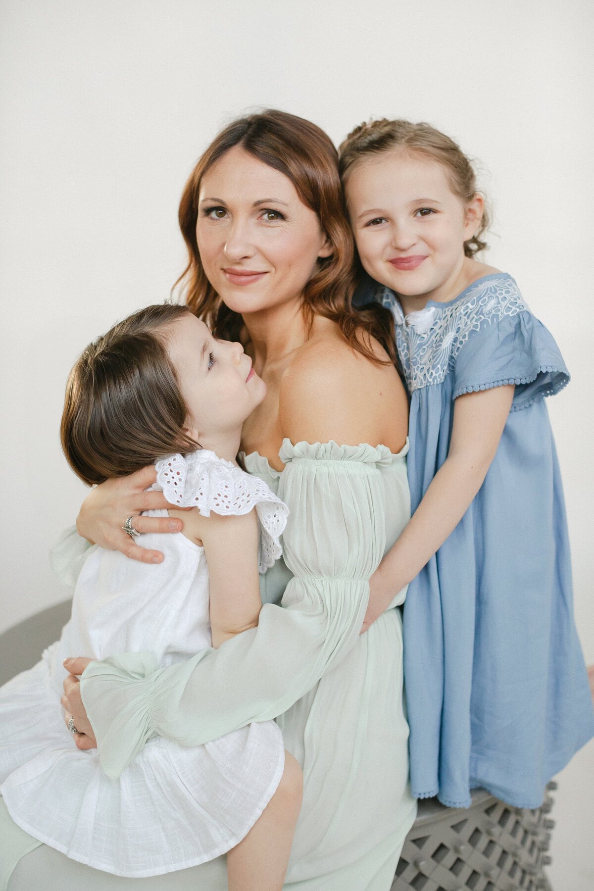 Mother poses with two children in teal off shoulder dress.