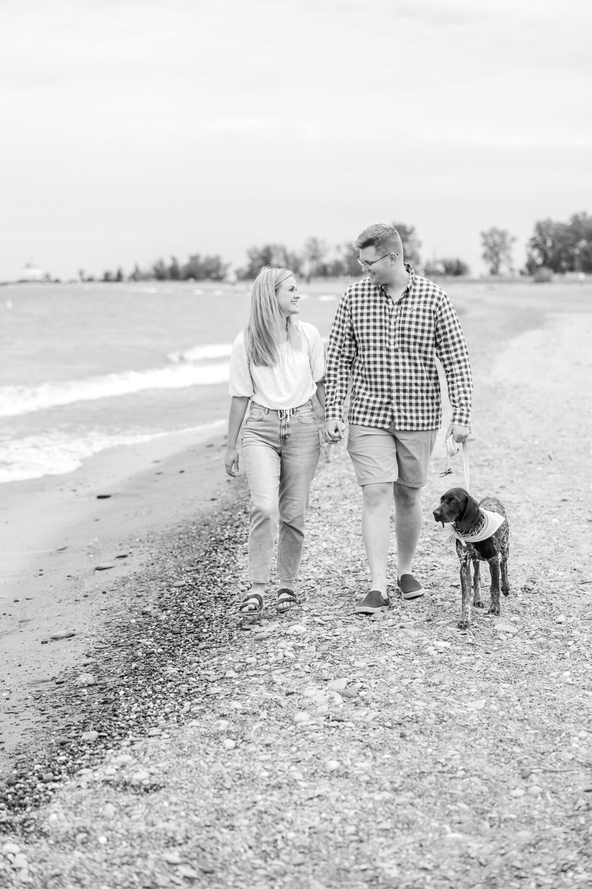 Light and airy beach engagement session with dog walking along the water at Mentor Headlands Beach