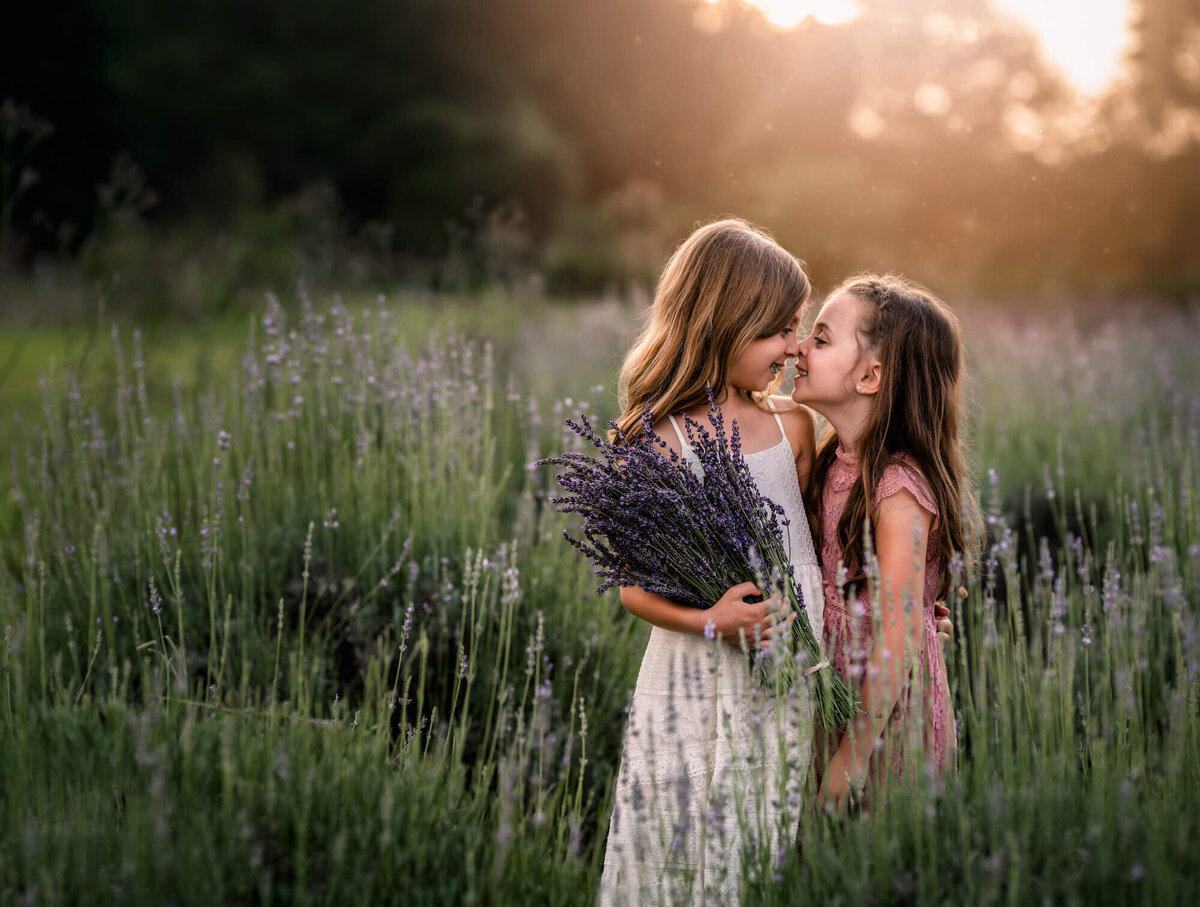 two young sisters boop noses while in a lavendar field