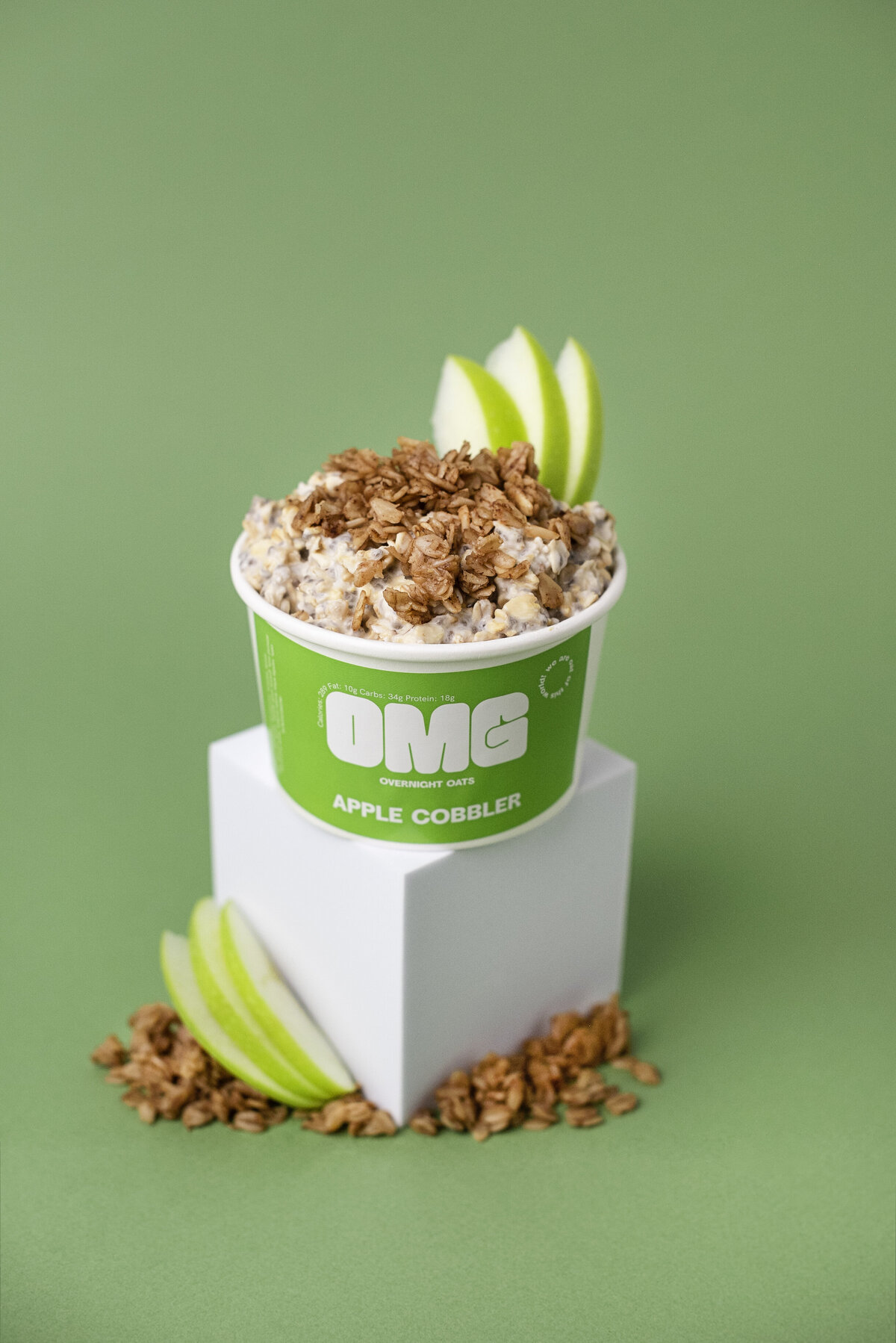 Green apple Cobbler over night oats topped with oats and green apple carton sting on white block