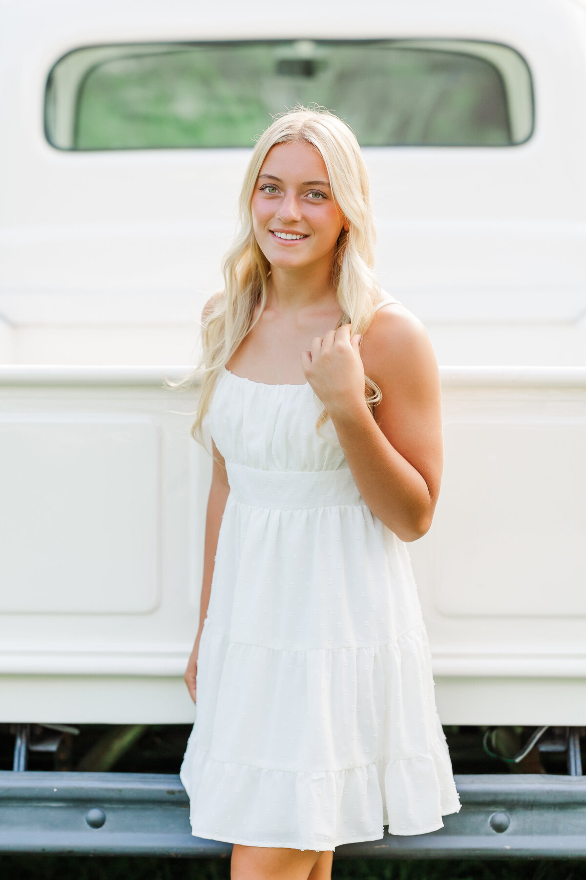 Girl in a white dress standing by a white vintage truck outdoors in North East, PA.