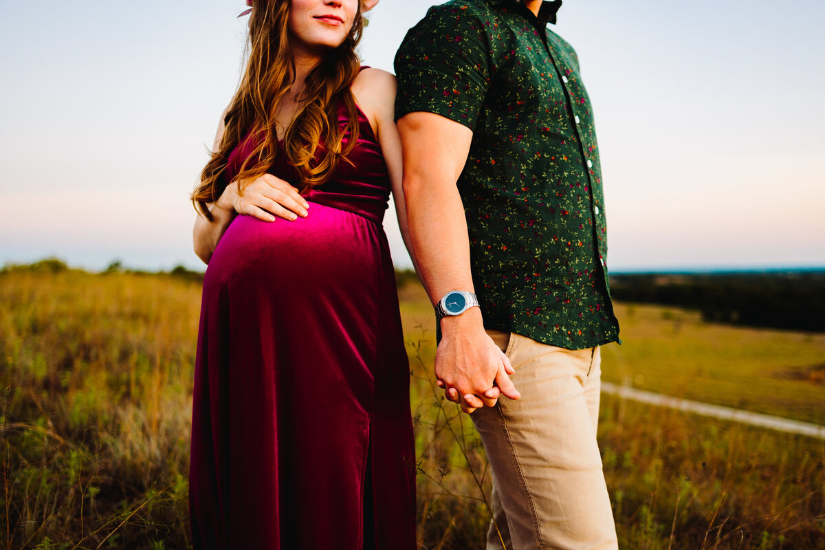 The joy of expecting with a maternity photographer in Albuquerque. The future mom is elegantly dressed in a red long dress, while the dad complements her with a green t-shirt. Their loving anticipation is beautifully showcased in this heartfelt photograph.