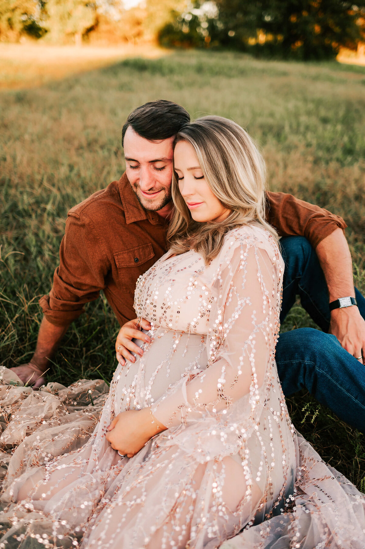 pregnant couple cuddling in field during Springfield MO maternity photography session