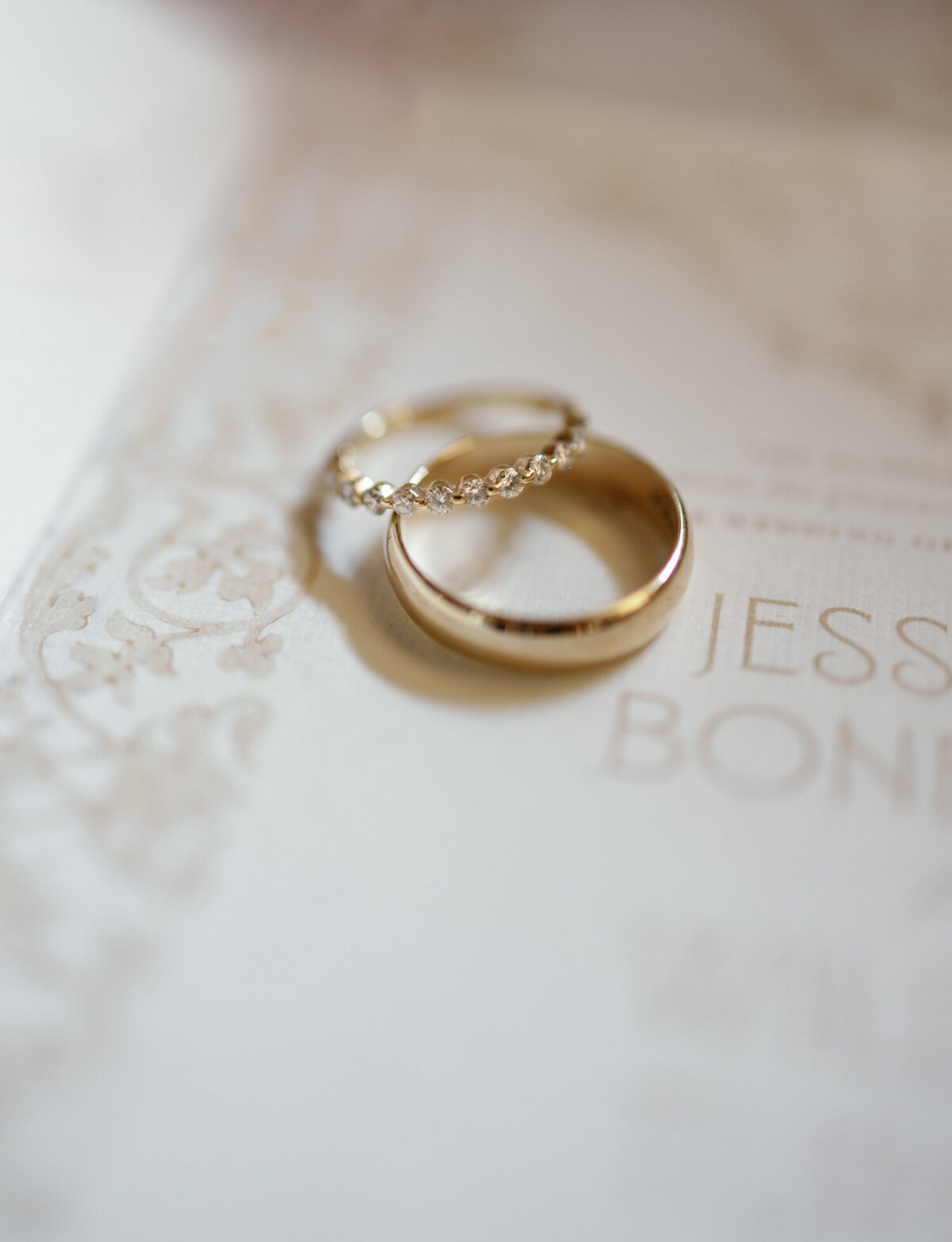 yellow gold rings nestled together over a beautiful wedding invitation in Detroit, Michigan